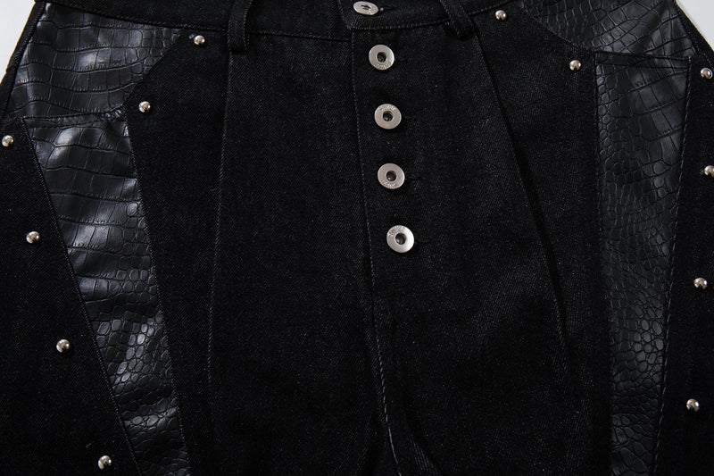 Close-up of black denim front with rivet-trimmed panel details and button fly