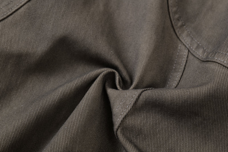 Close-up of washed olive-brown denim texture and curved seam stitching