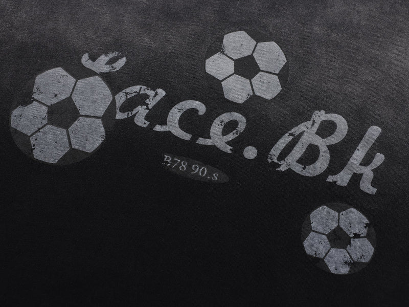 Close-up of black soccer graphic print with faded lettering on the tee