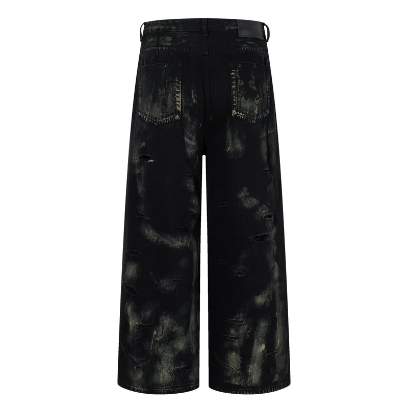 Back view of black wide-leg jeans with patch back pockets and paint-wash distressing