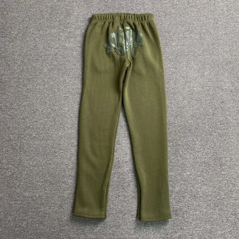 Syna World Olive Green Drawstring Jogger Pants for kids, crafted from soft cotton-polyester fleece, feature an elastic waistband and a light skull and crossbones graphic on the back, displayed flat on a gray textured surface.