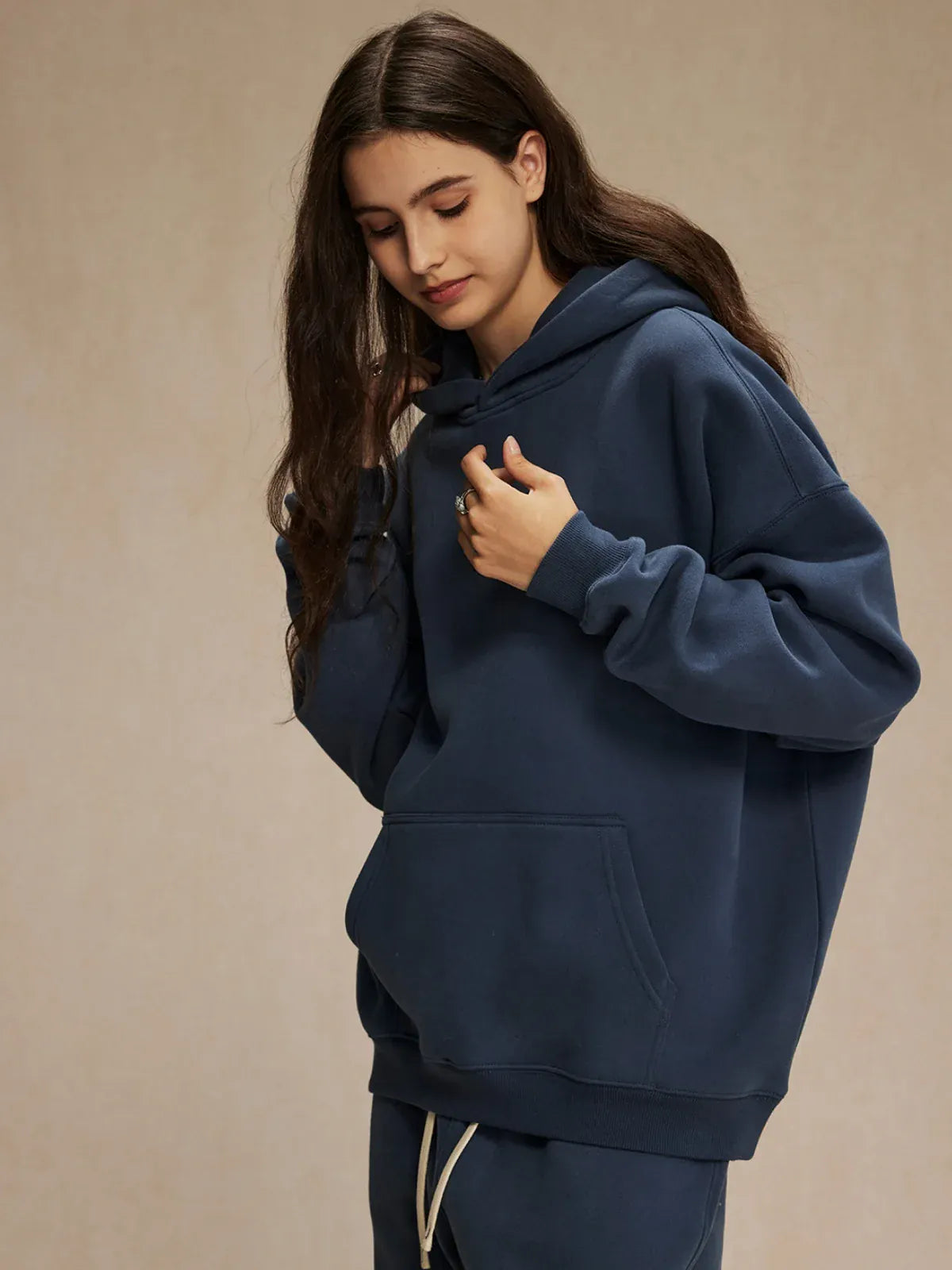 A person with long brown hair wears a Custom Anime Character Navy Hoodie - Personalized 350GSM 100% Cotton Pullover and matching pants, standing against a plain beige background.