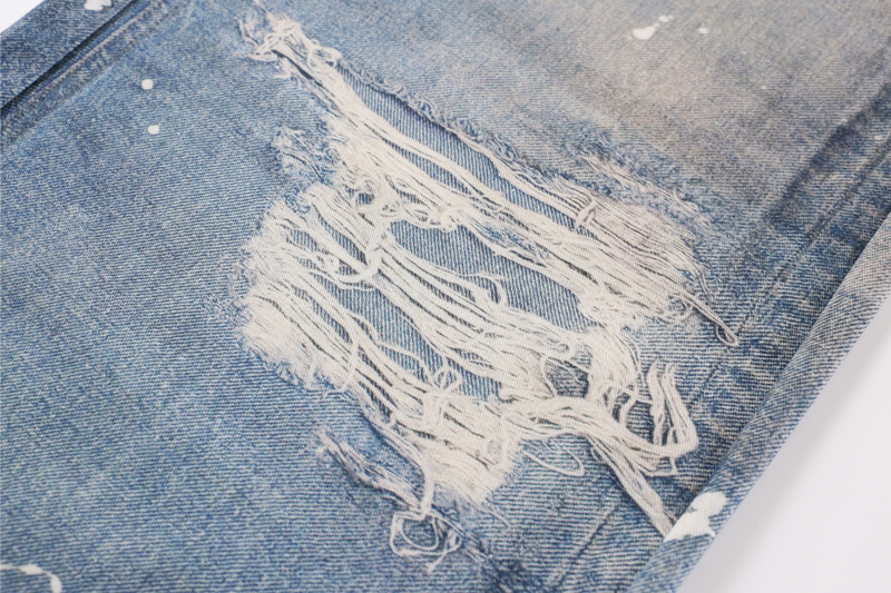 Close-up of shredded distressed patch on faded blue denim