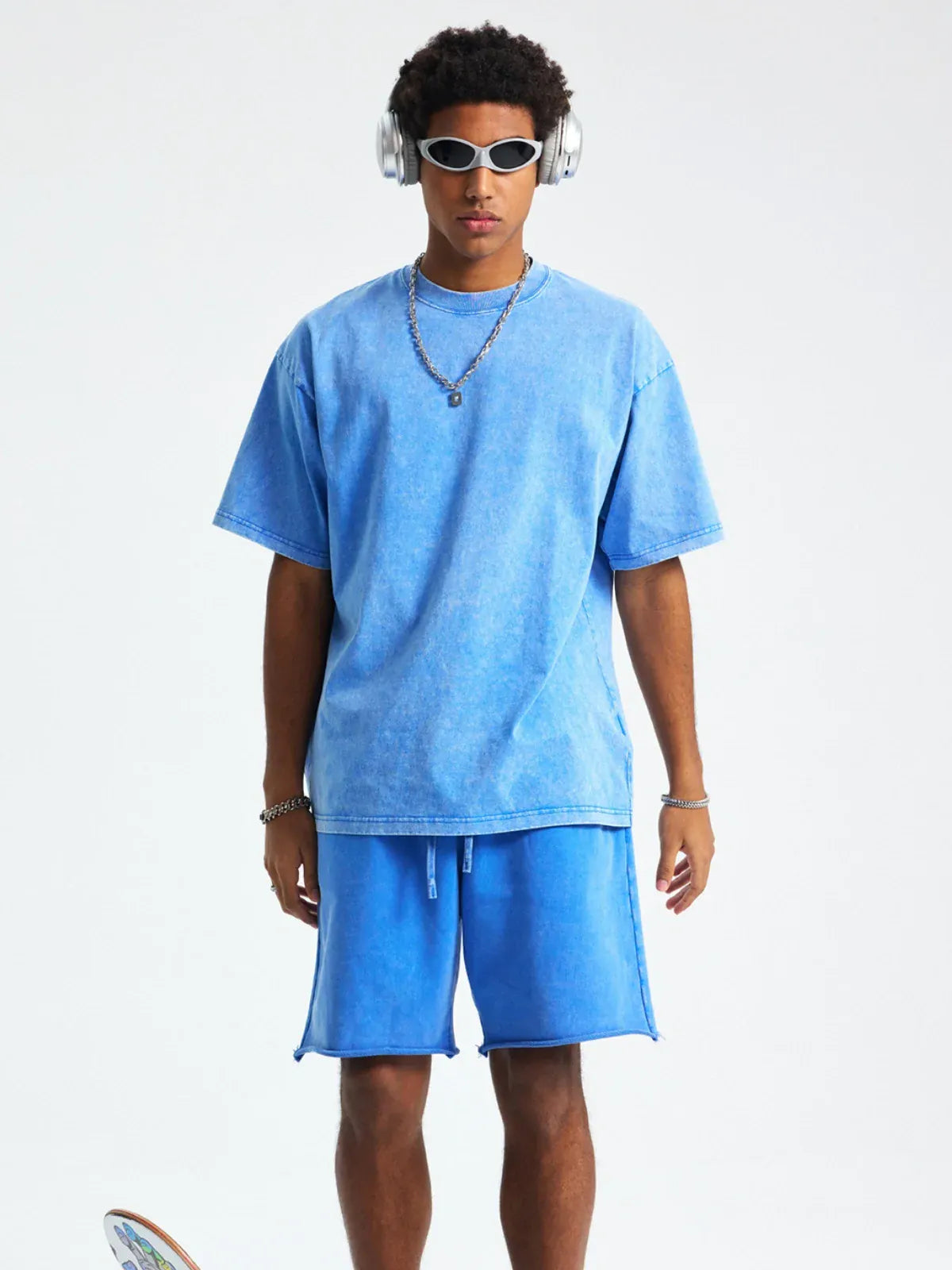 A person stands facing forward against a plain white background, wearing headphones, white sunglasses, and a Custom Anime Character Blue Washed T-Shirt - Personalized Anime Style Tee with matching blue shorts.