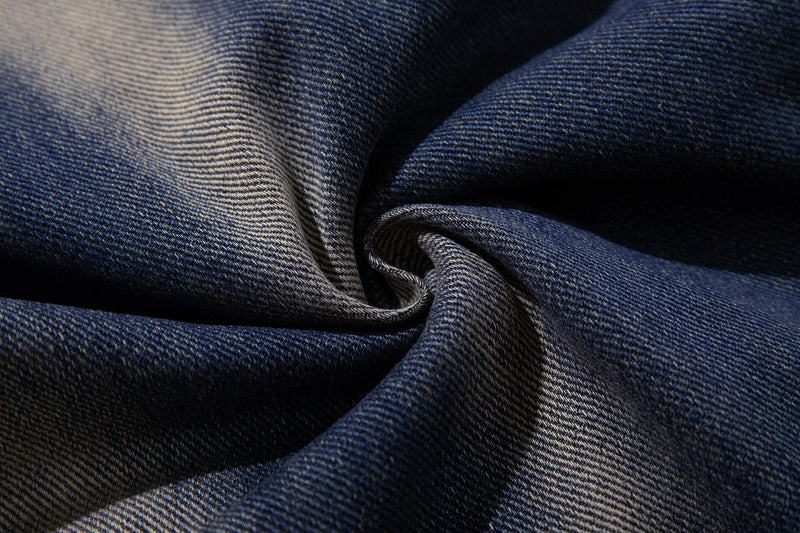 Close-up of folded blue denim fabric showing the jeans texture and smoke-fade wash