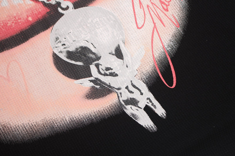 Close-up of black oversized T-shirt with rhinestone lip graphic, white skull detail, and pink Y2K streetwear print