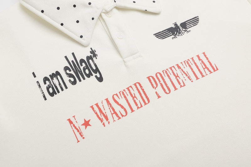 White graphic polo shirt with polka dot collar and bold distressed slogan print
