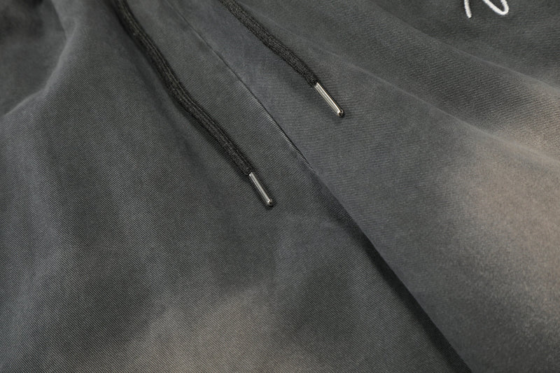 Close-up of drawstrings and front seam on washed charcoal cargo pants