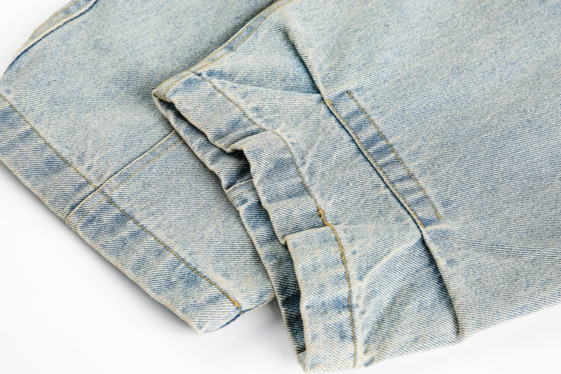 Close-up of cuffed denim hem and side seam on light blue jeans