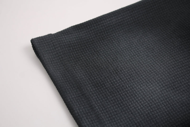 Close-up of dark washed waffle-knit tee fabric with a textured oversized streetwear finish