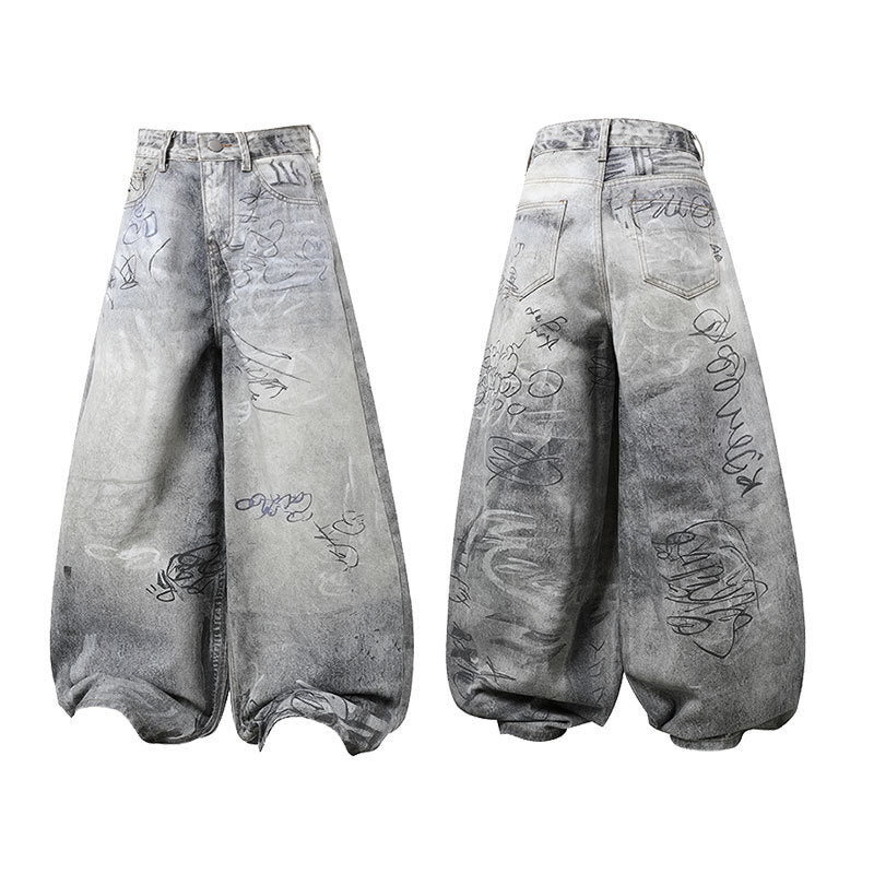 Front view of grey washed wide-leg denim pants with all-over graffiti script print and curved balloon silhouette