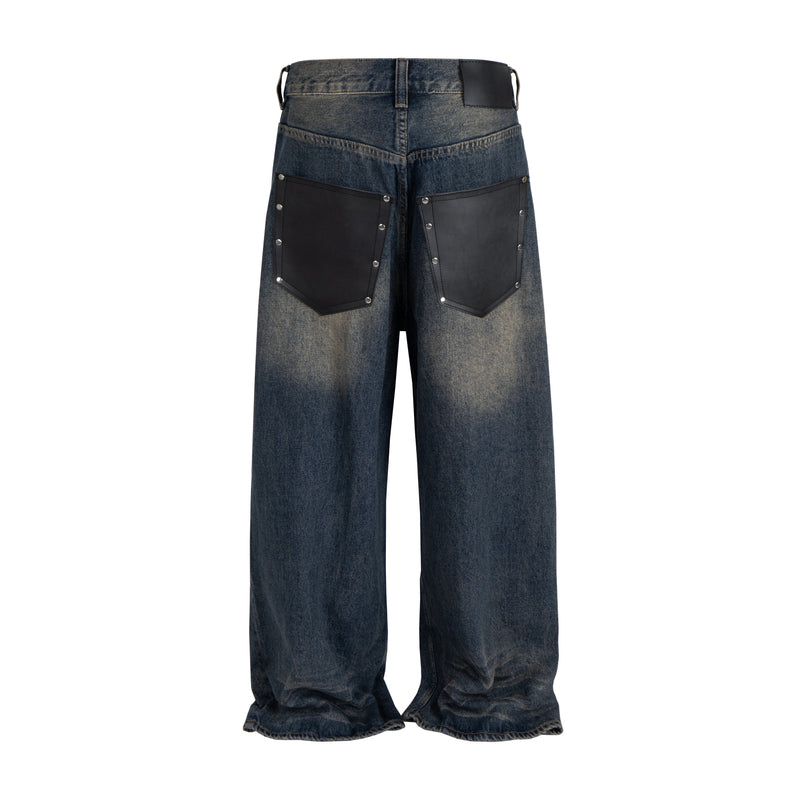 Back view of wide-leg blue denim jeans with black leather patch pockets and faded distressing