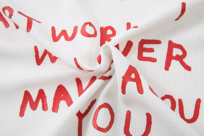 Wrinkled white tee fabric with red back text and partial flame doodle close-up