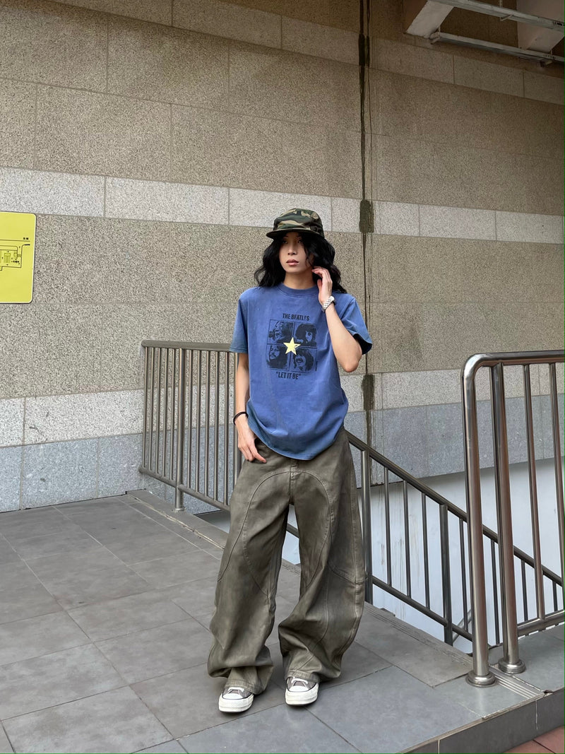 Model wearing washed olive-brown curved-panel wide-leg jeans with a blue graphic T-shirt