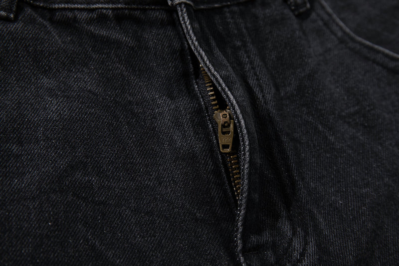 Close-up of the front fly zipper on black denim jeans