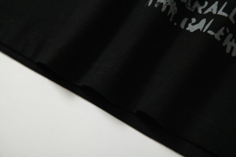 Black graphic crop tee with white graffiti-style print and soft draped fabric detail
