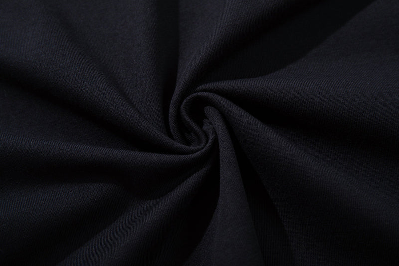 Black cotton T-shirt fabric close-up with a soft spiral fold and textured knit detail