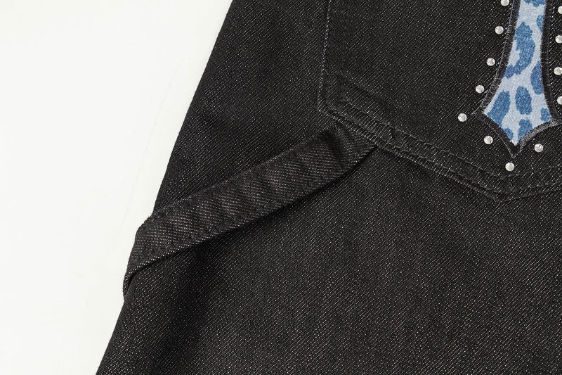 Close-up of one back pocket with blue cross appliqué and silver studs