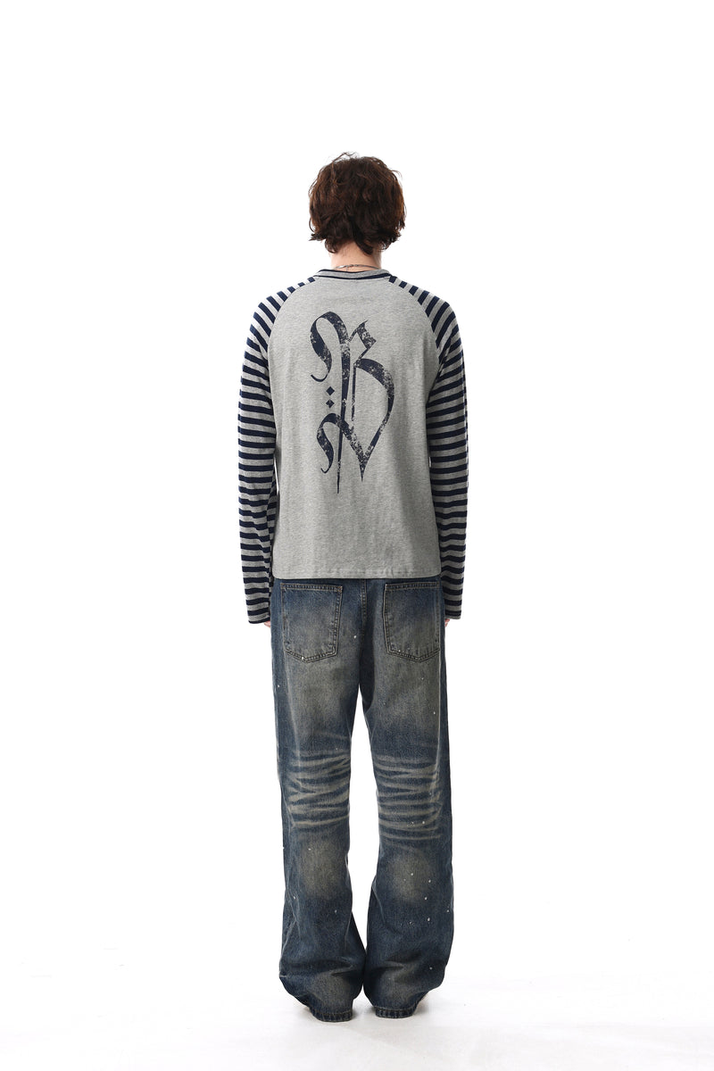 Back view of gray raglan tee with navy striped sleeves and gothic cross print on model
