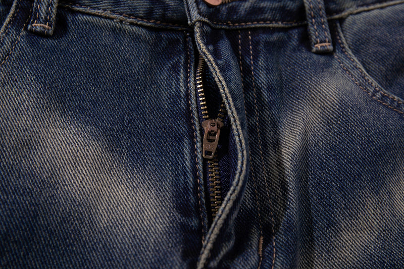 Close-up of the front zipper fly and top waistband on blue denim jeans