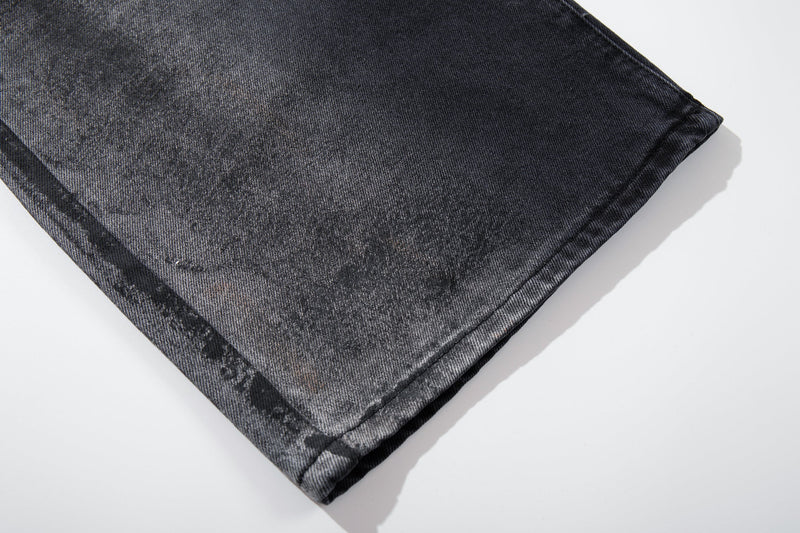 Close-up of a wide leg hem on dark washed jeans with mottled smoky texture