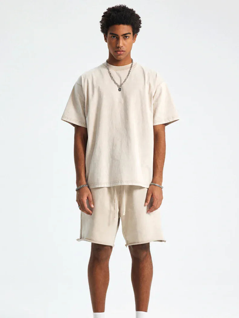 A man stands facing forward in a Custom Anime Character Beige Washed T-Shirt - Personalized Anime Style Tee, paired with matching shorts and accessorized with a necklace and bracelets, against a plain white background.