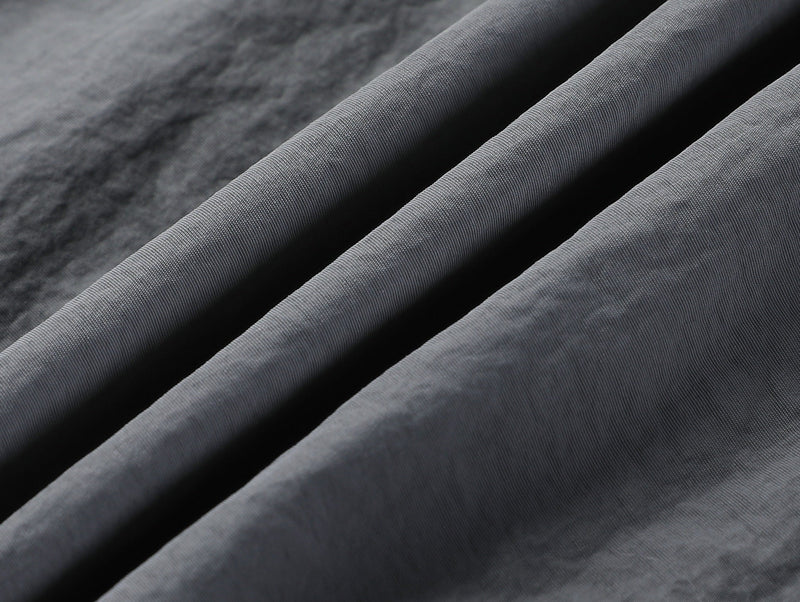 Close-up of gray fabric with diagonal draped folds and fine texture