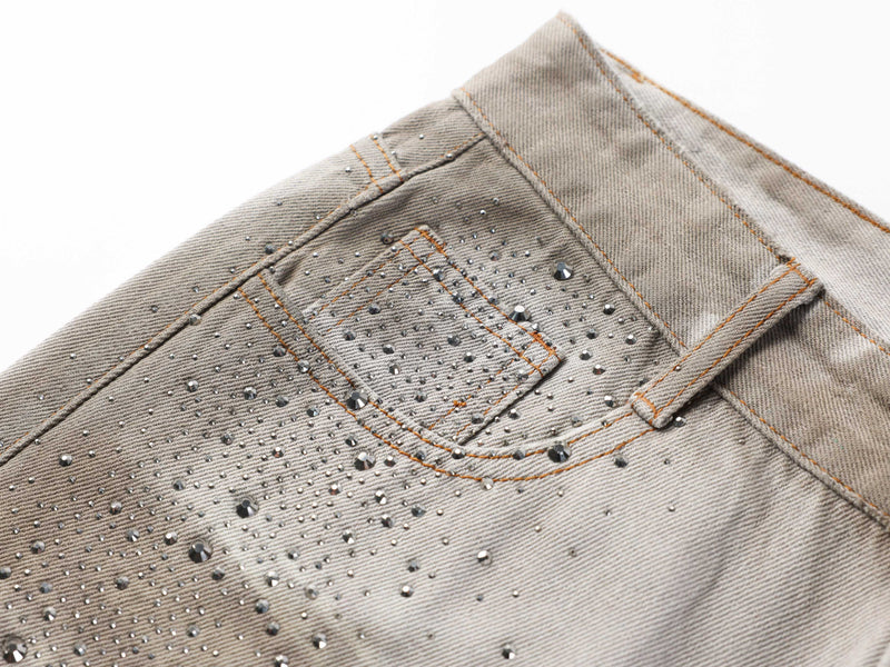 Close-up of the back pocket on washed denim pants with rhinestone detailing