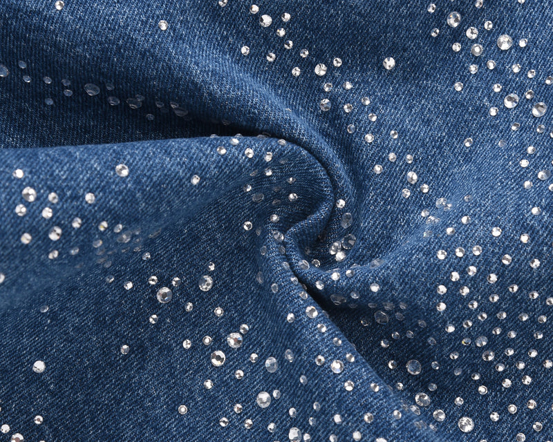Close-up of blue denim fabric with scattered rhinestones and fold detail
