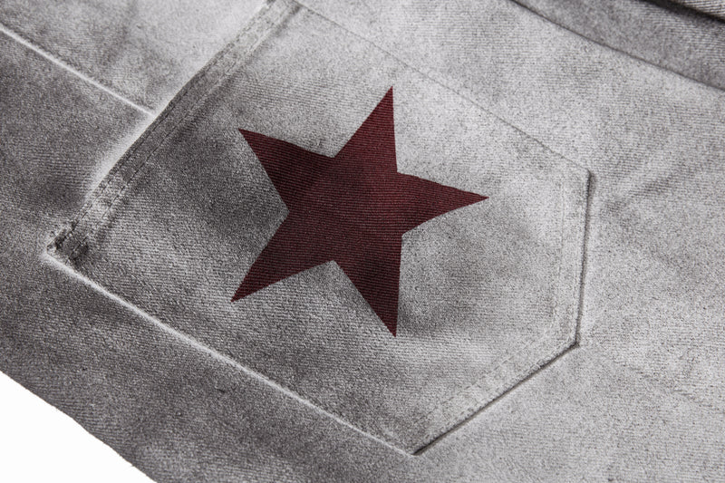 Close-up of red star print on a back pocket of gray washed denim pants