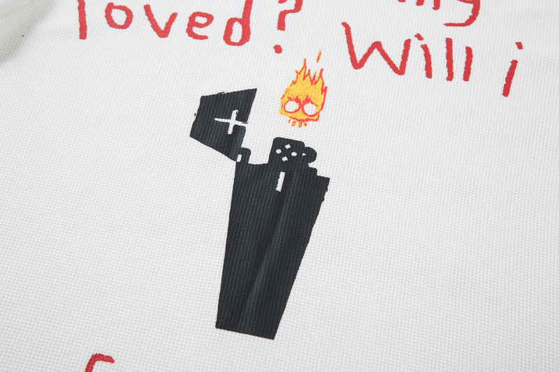 Close-up of front graphic showing black doodle figure and small flame icon on white tee