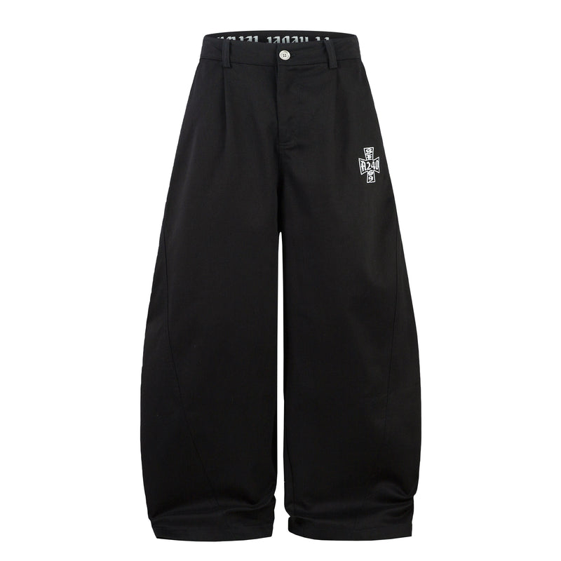 Front view of black wide-leg pants with curved seam lines, button closure, and side graphic embroidery