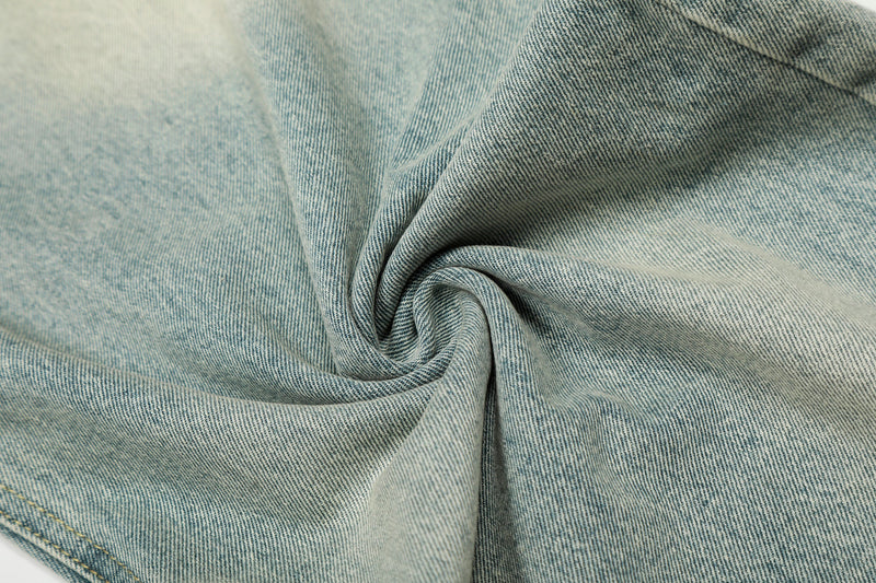 Close-up of twisted light wash denim fabric with faded texture and seam lines