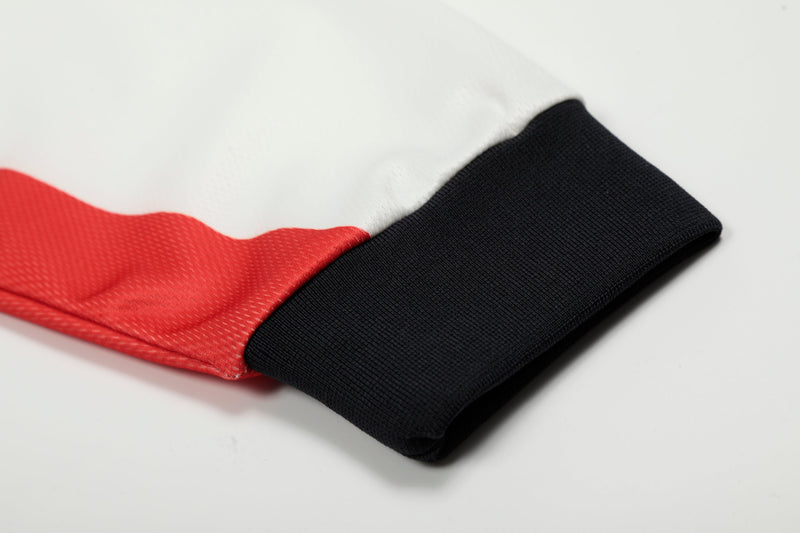 Close-up of black cuff and red side panel on a white football jersey sleeve