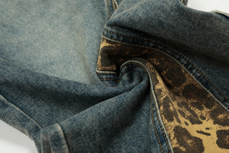 Close-up of folded denim fabric showing blue wash and leopard-print panel