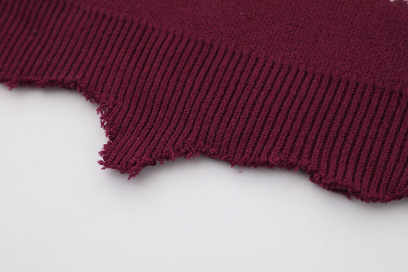 Close-up of burgundy sweater distressed ribbed hem with frayed edges