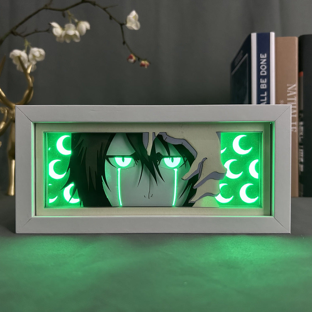 The Bleach Anime Light Box showcases Ulquiorra Cifer with green eyes and tears amid crescent moons on a green backdrop. Its 3D effect is enhanced by blurred books and a plant, featuring a 16-color adjustable LED light for ambiance.