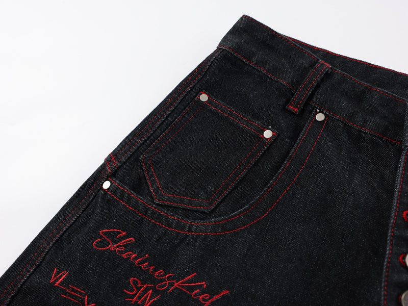 Close-up of front pocket and waistband on black denim with red stitching and rivets