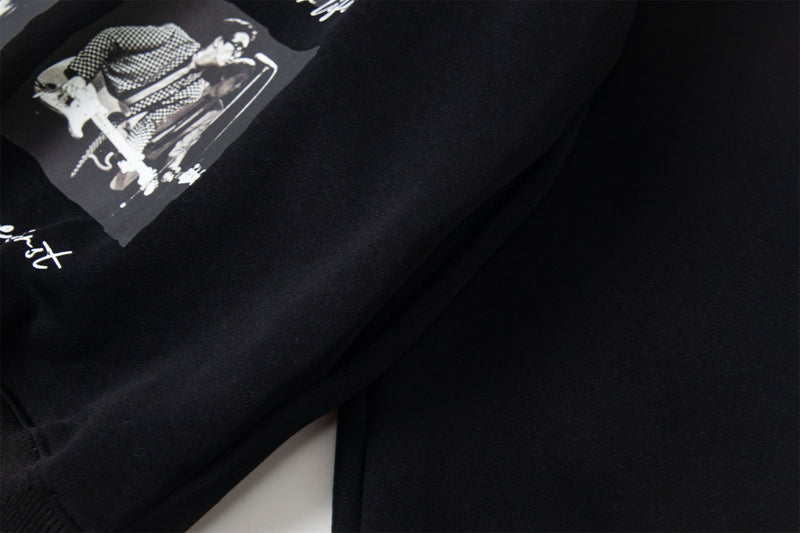Close-up of black hoodie front graphic beside a sleeve seam