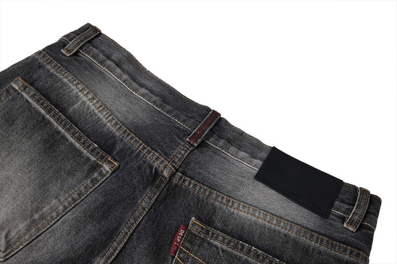 Close-up of back waistband and pockets on faded black jeans with belt loops and patch