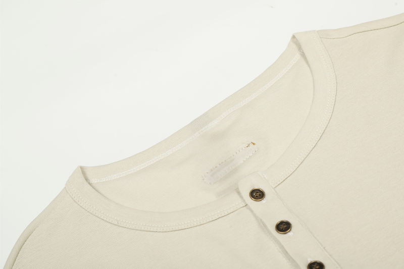 Cream Henley tee neckline close-up with button placket and stitched shoulder seam