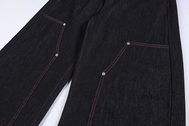 Close-up of the back leg pockets and pink topstitching on black denim pants