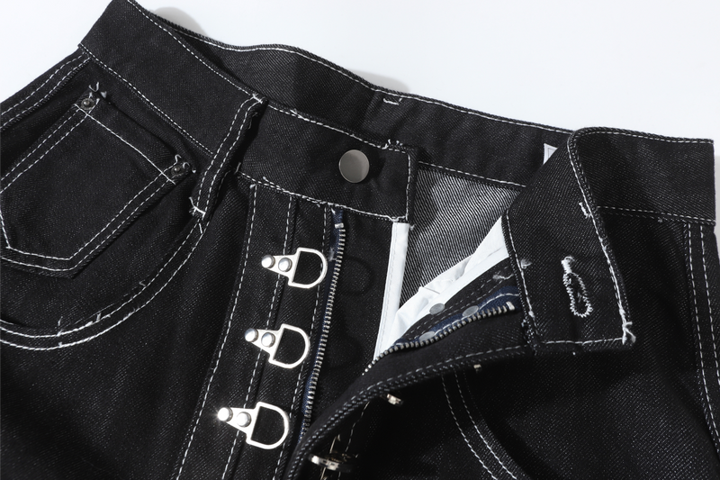 Front waistband close-up showing black denim, metal buckles, and partially open fly