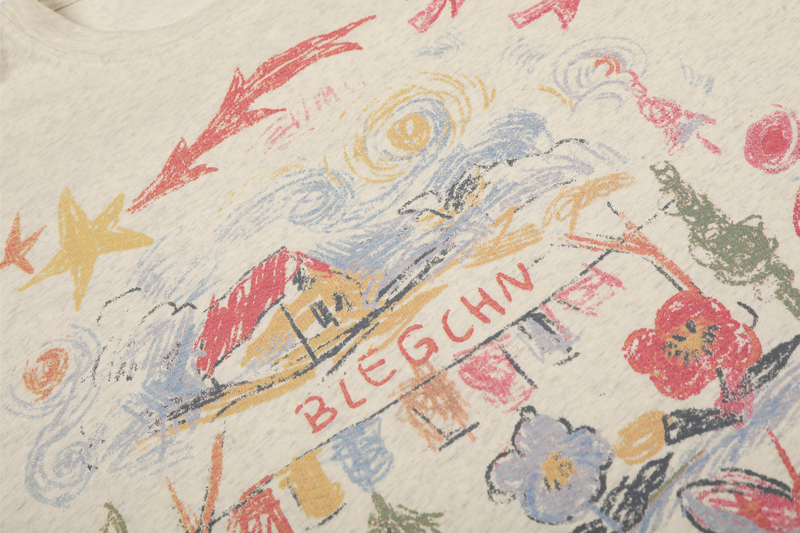 Close-up of vintage sketch print on cream tee with stars, clouds and house