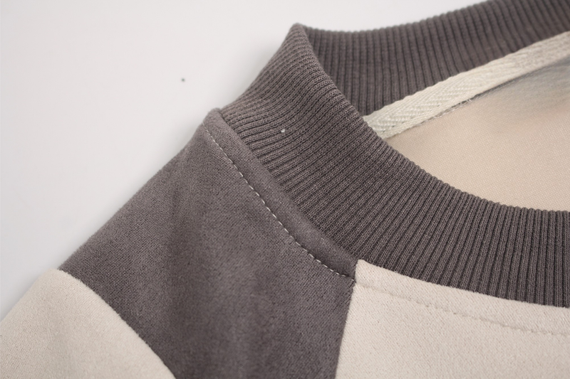 Close-up of a gray suede panel tee with ribbed crew neck and contrasting cream and charcoal fabric blocks