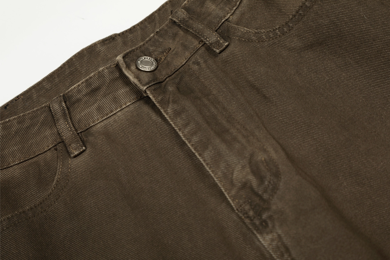 Close-up of front waistband on brown cargo pants showing snap closure and topstitching