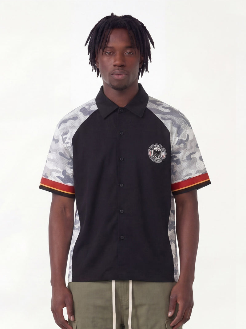 Black streetwear button-up shirt with gray camo sleeves and a circular eagle patch, worn by a male model