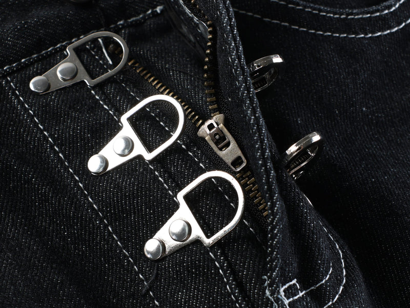 Close-up of the front buckle hardware and zipper area on dark wash denim shorts
