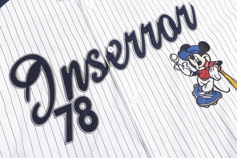 Close-up of Inserror 78 graphic and Mickey patch on white pinstripe shirt front