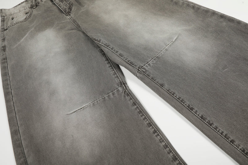 Close-up of front leg panels on grey washed wide-leg jeans showing curved seams and fading